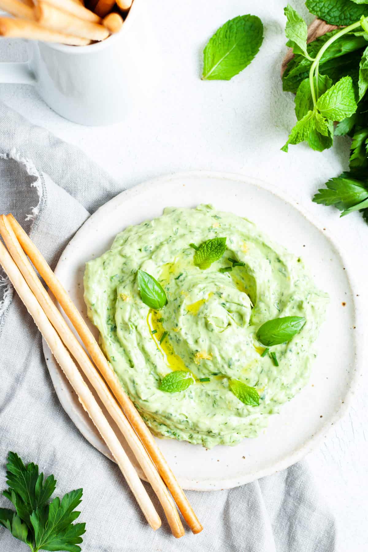 Green goddess dip with grisini on a plate