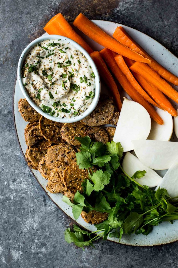 Bowl of miso cauliflower dip on a platter with carrots and vegies for dipping