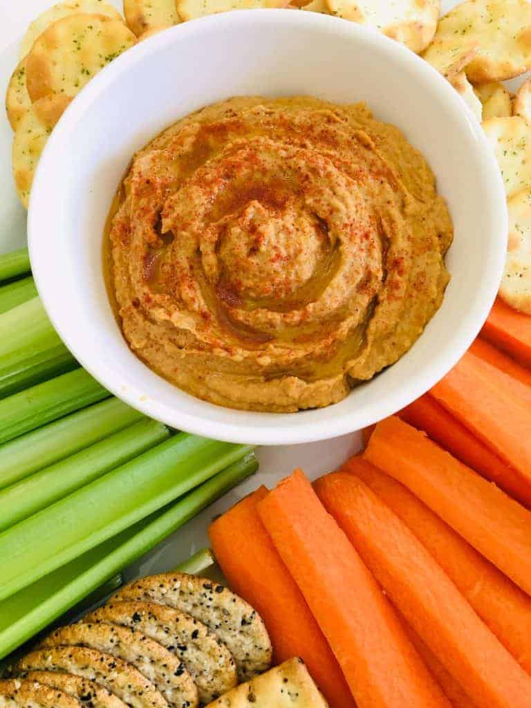 Bowl of peanut butter dip and vegetable sticks - carrots and celery- and chips