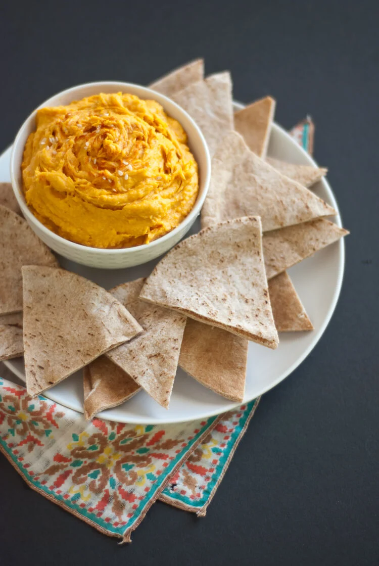Bowl with sweet potato dip and tortilla chips on a plate